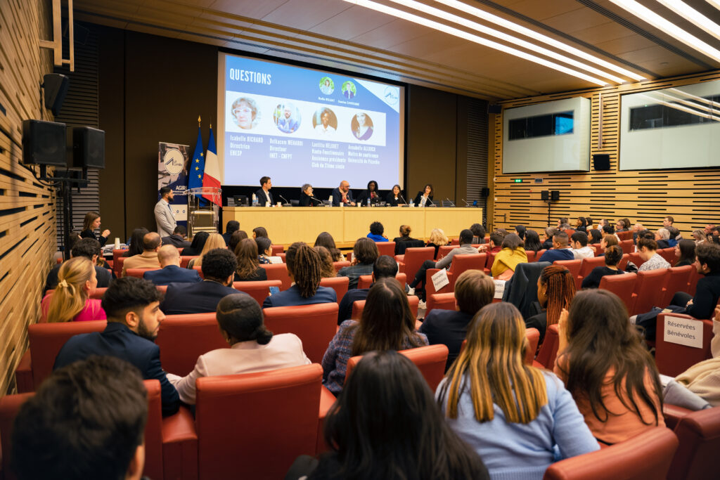 Photo d'une table ronde avec 6 personnes sur une estrade et une assemblée